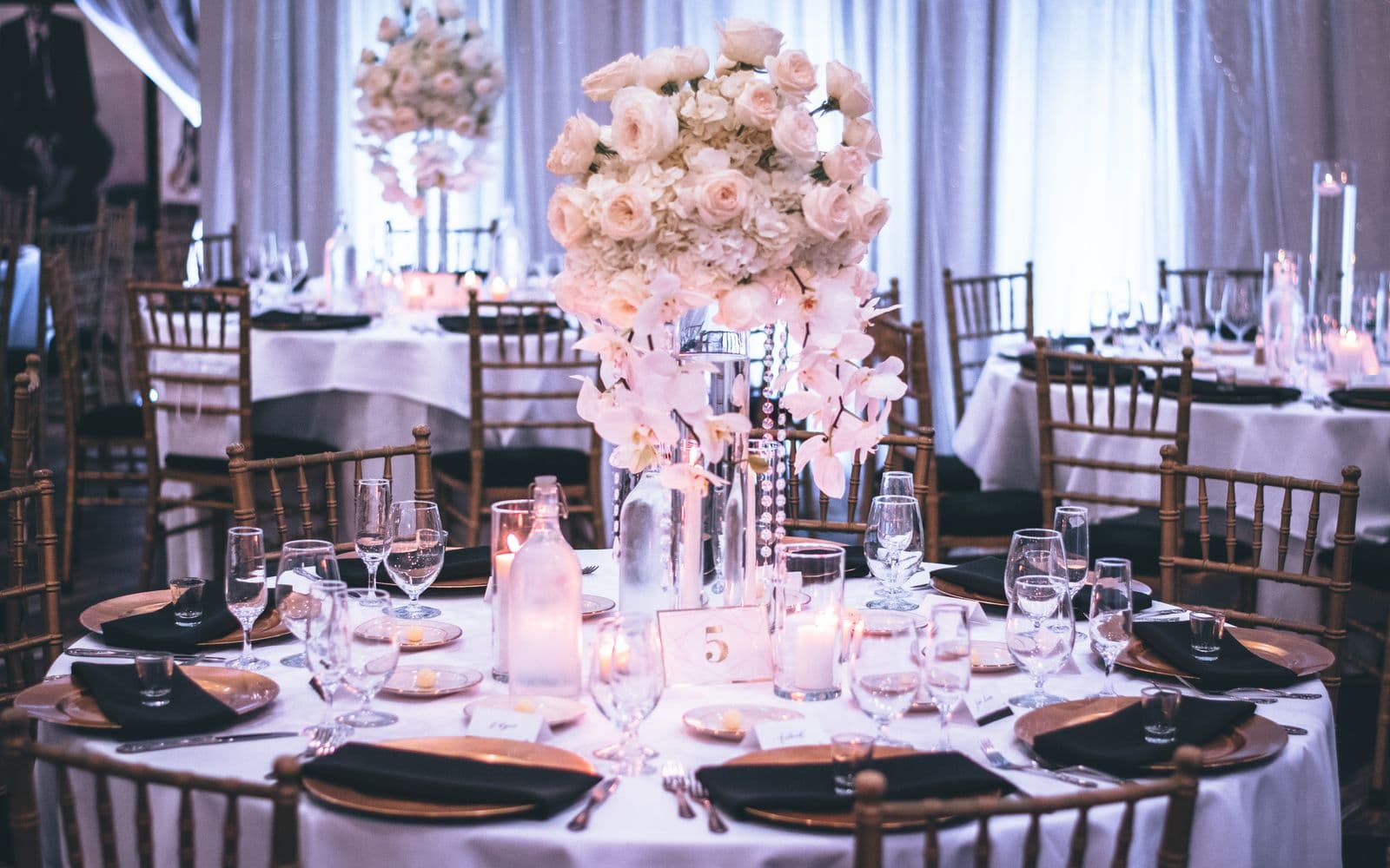Festlich gedeckte Hochzeitstafel mit weißen Blumen und Kerzen in einem Ballsaal