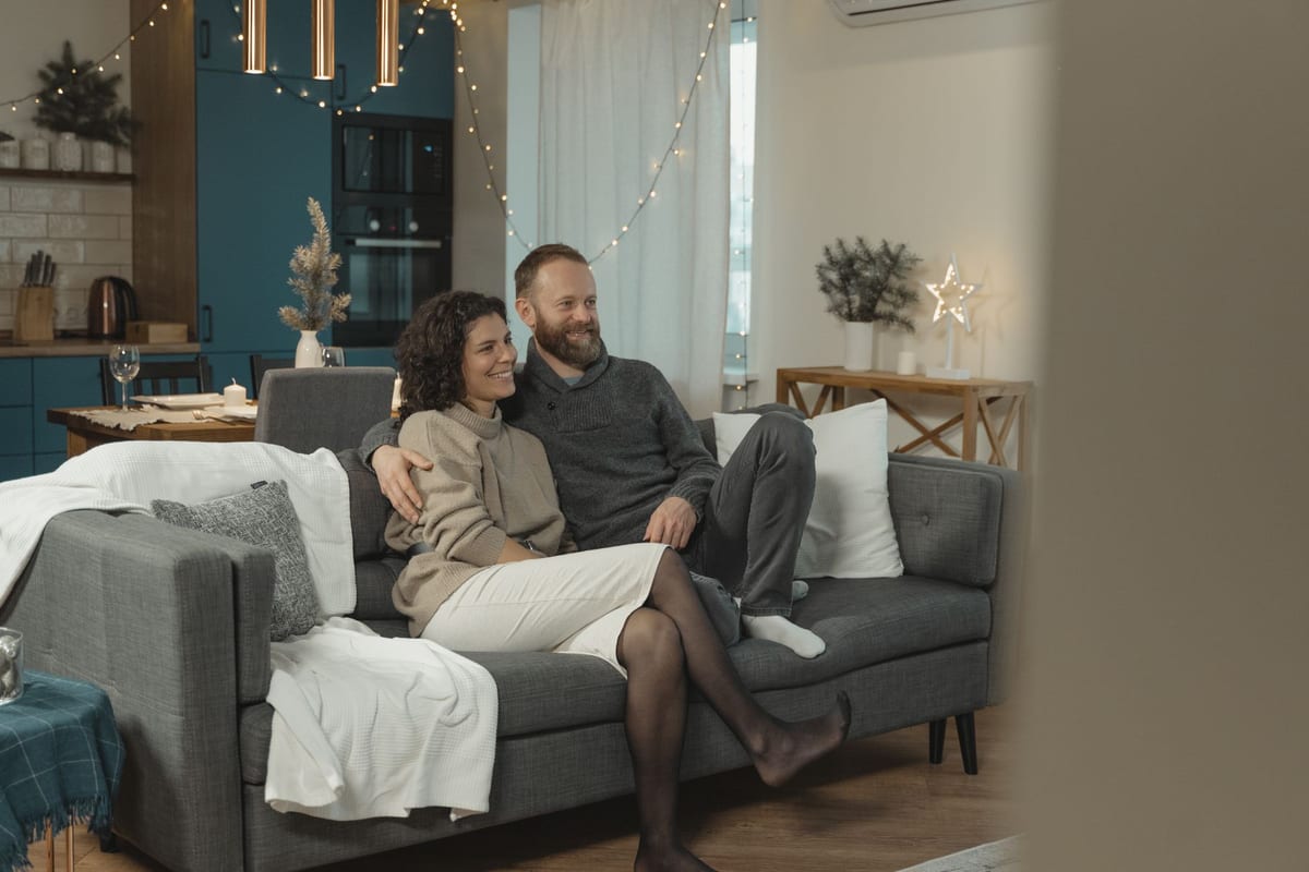 Paar sitzt entspannt auf dem Sofa in einer gemütlichen Wohnung